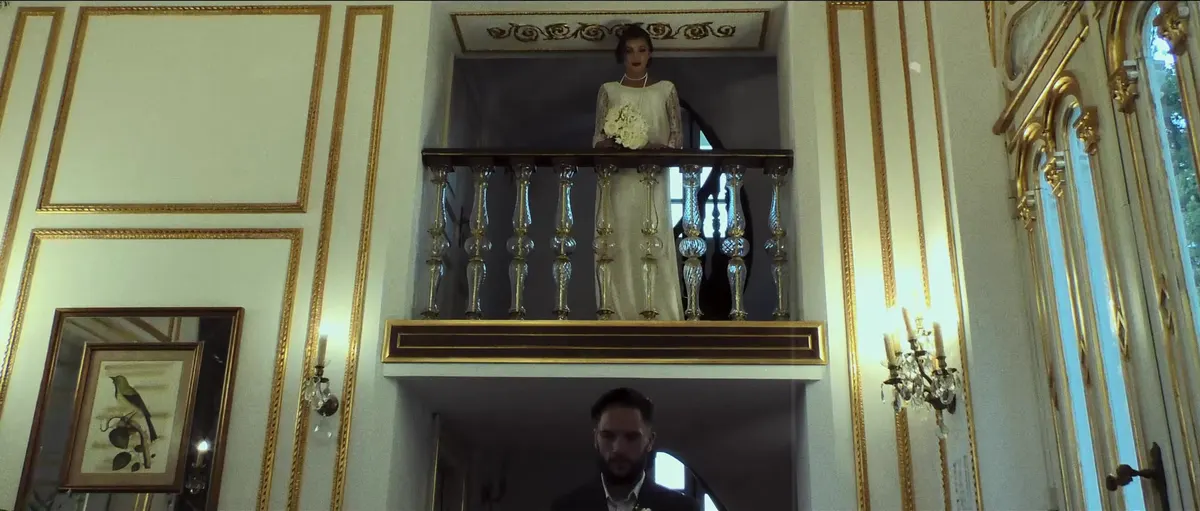 La mariée au balcon d'un salon doré, le marié l'attend en contrebas, film Coco Elopement