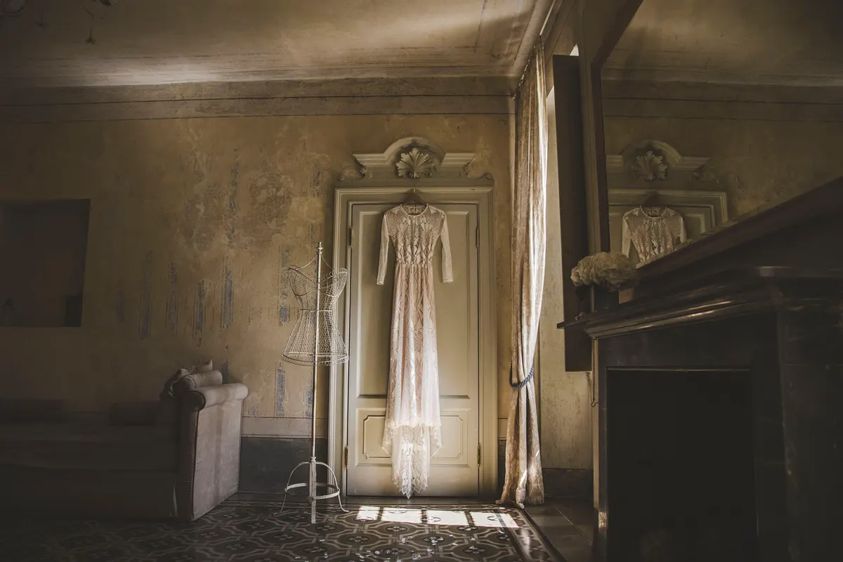 Robe de mariée suspendue dans un salon ancien aux boiseries patinées
