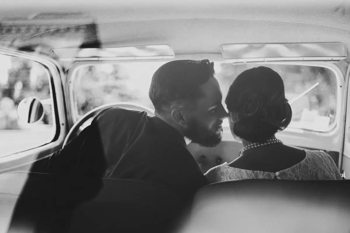 Les mariés à l'arrière d'une voiture ancienne, en noir et blanc