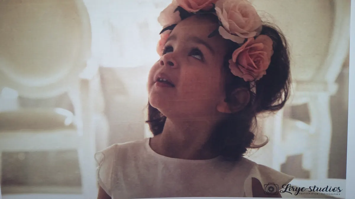 Une petite fille couronnée de fleurs lève les yeux pendant la cérémonie