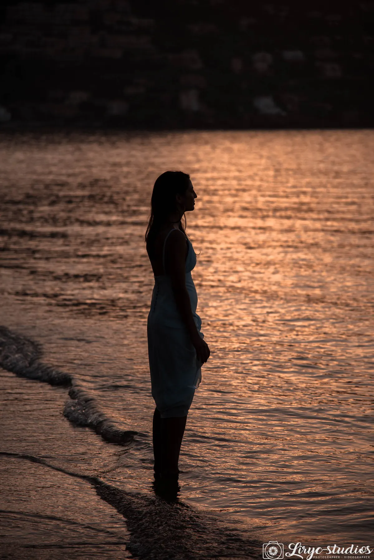 Silhouette de la mariée les pieds dans l'eau, au coucher du soleil