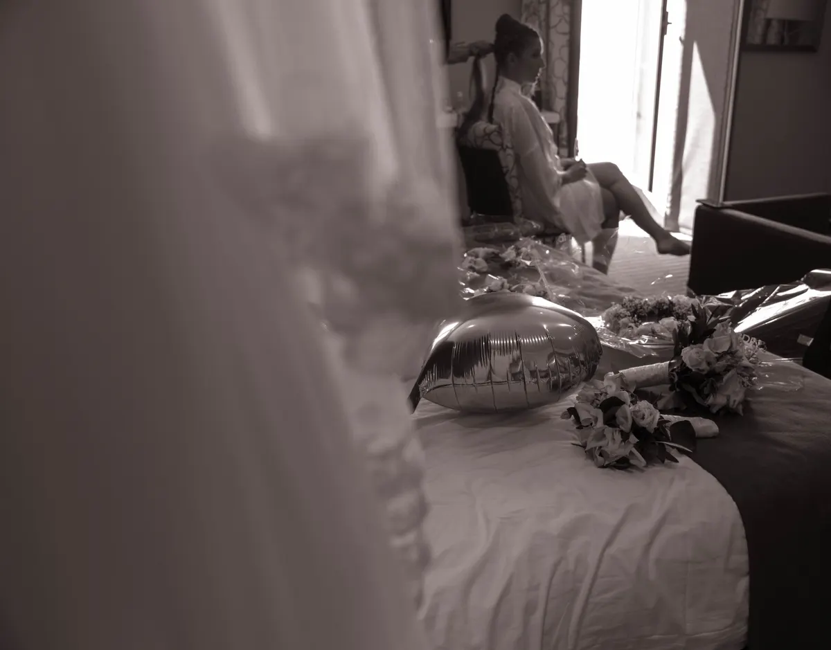 Préparatifs de la mariée dans une chambre baignée de lumière, en sépia