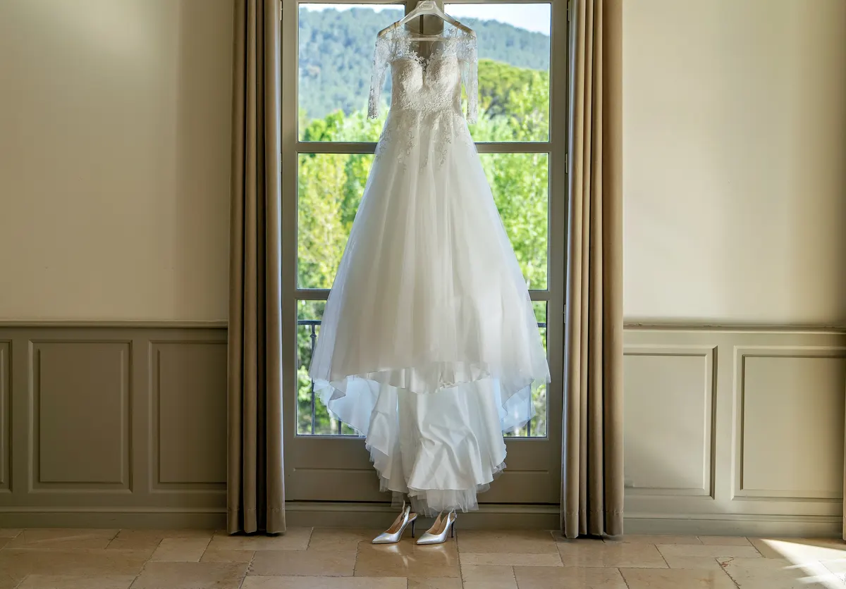 Robe de mariée devant une fenêtre aux rideaux tirés